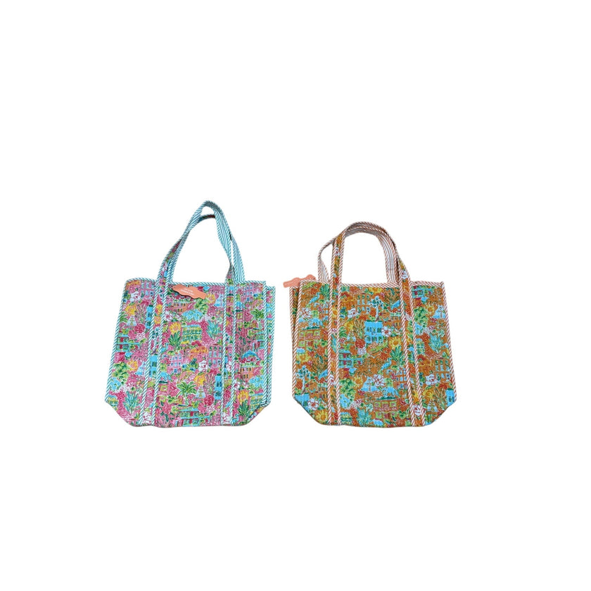 Two small tote bags with colorful illustrated map-like prints and light blue handles, shown side by side on a plain white background.