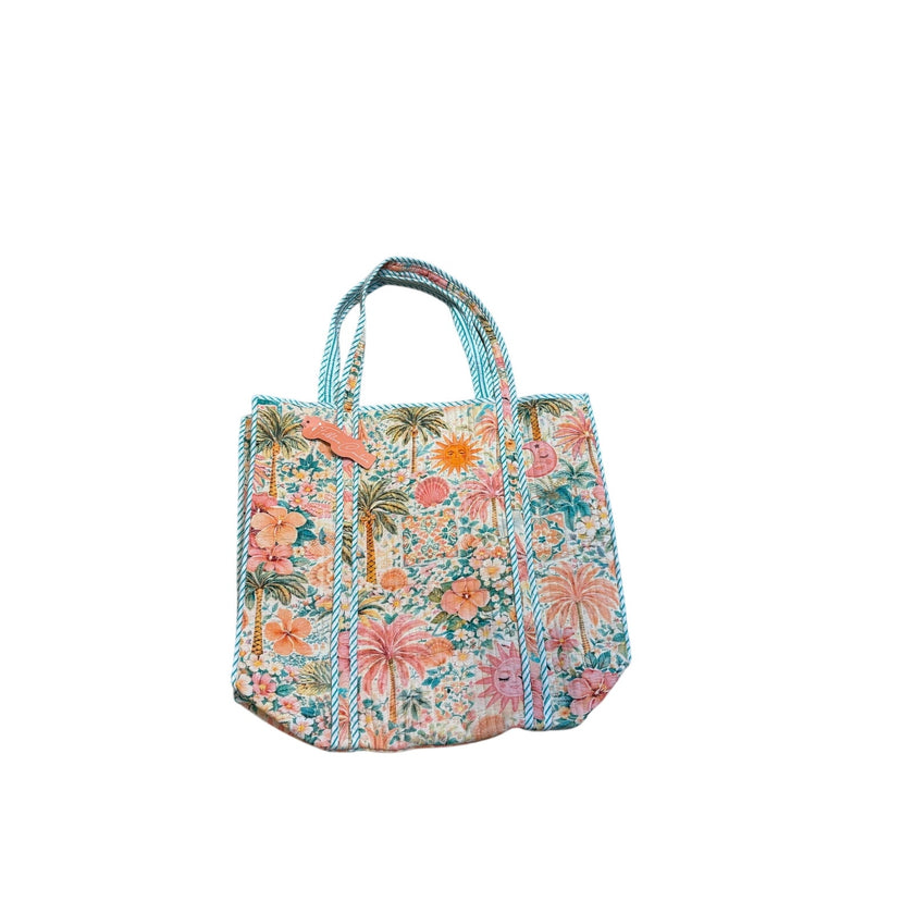 A small tote bag with a colorful tropical floral and palm tree print, featuring light blue braided looking handles, set against a plain white background.