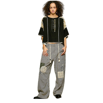 Woman wearing a black top and patterned gray pants on a white background